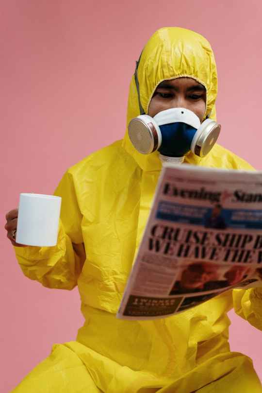man in yellow protective suit holding a newspaper